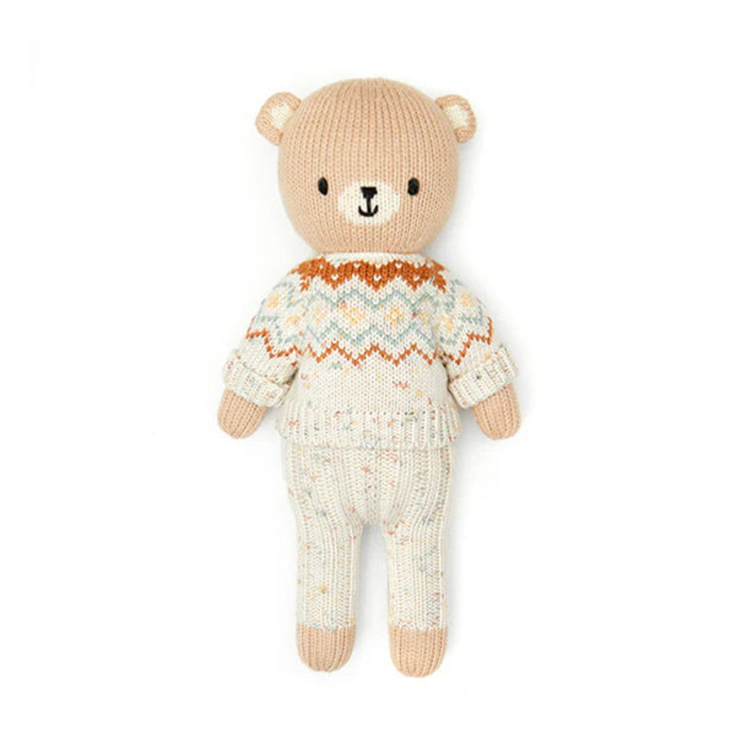 Knitted teddy bear wearing a patterned sweater on a white background