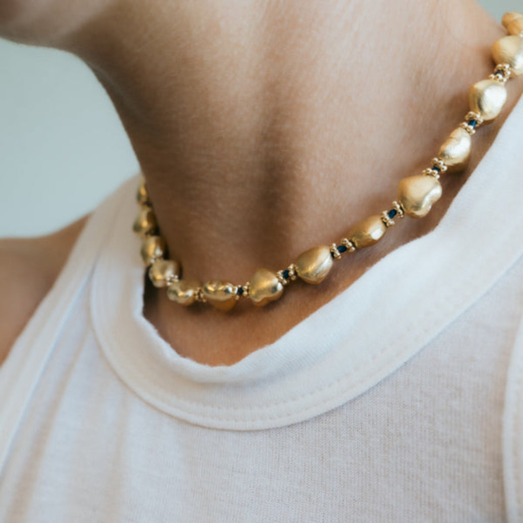 Gold necklace with heart-shaped beads on a light background